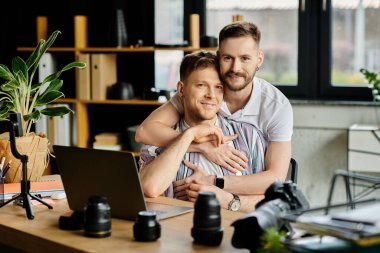 Two men in casual attire, happily collaborating on a laptop in an office. clipart