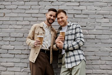 Gündelik giysiler içindeki mutlu eşcinsel çift açık havada içkinin tadını çıkarıyor..