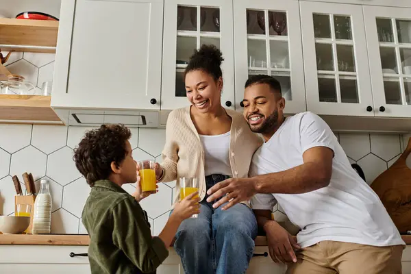 stock image An African American man and woman sit on a kitchen counter with a young boy.