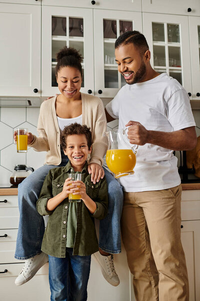 A man, woman, and child happily stand in a kitchen.