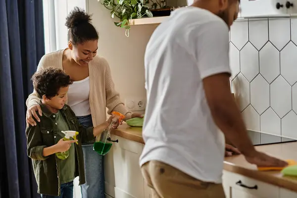 stock image African American family cleaning in kitchen with young boy.