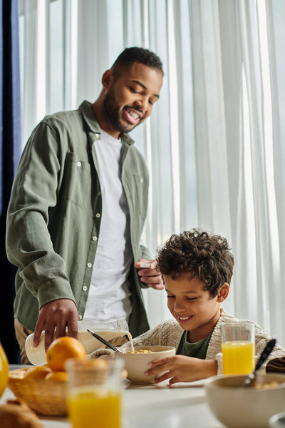 Мужчина и мальчик едят дома на кухне.