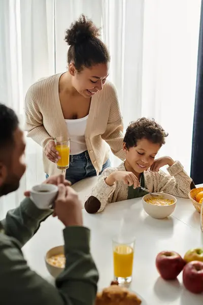 stock image African american family gathered around a table, enjoying a meal together.