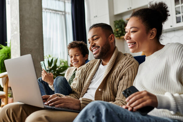 Couple engrossed in laptop on couch, with son.