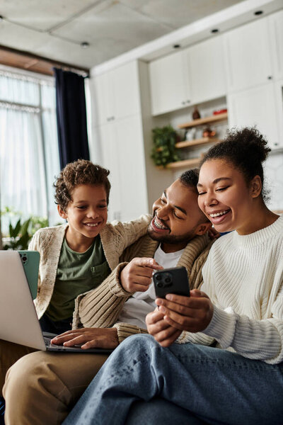 Африканская американская семья наслаждается мобильным телефоном вместе на диване.