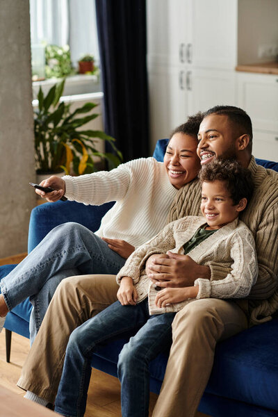 Мужчина и женщина сидят на синем диване с ребенком.