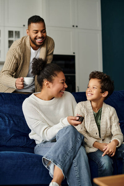 Мужчина, женщина и мальчик хорошо проводят время на синем диване.