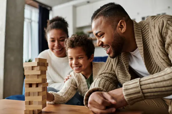 stock image African american family happily playing and constructing with wooden blocks.