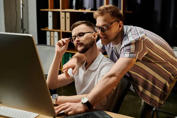 stock image Two men in casual office attire engage with laptop screen.