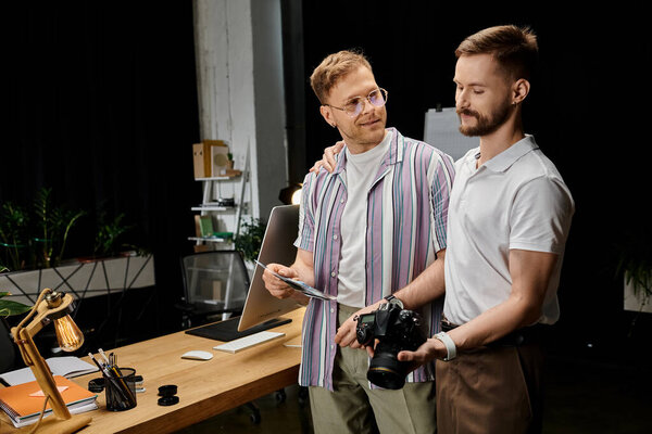 Two men in casual attire working side by side at a desk.