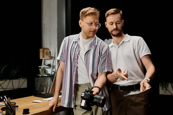 stock image Two men in casual attire standing side by side, engrossed in a collaborative work project.