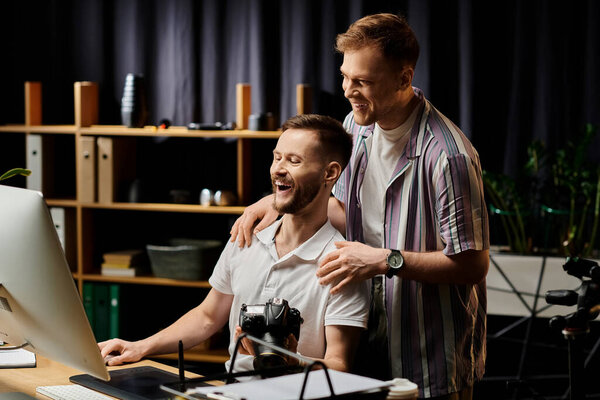 Two men in casual attire engrossed in viewing computer screen.