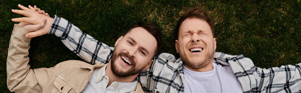 Двое мужчин в стильной одежде лежат на ярком зеленом поле.