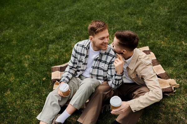Пара мужчин в повседневной одежде, сидящих на пышном травяном поле.