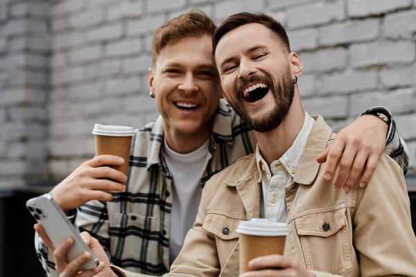 Двое мужчин держат мобильный телефон на улице.