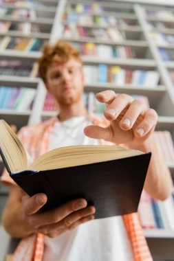 Kütüphanede kitap okumaya dalmış genç bir adam..