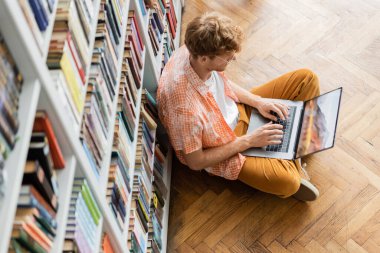 Young student immersed in laptop work on the floor. clipart