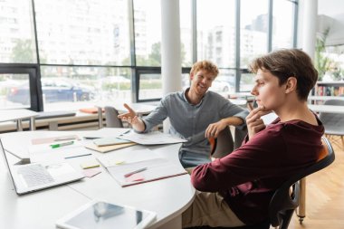 Modern ofis ortamında bir masada iş toplantısına dalmış iki adam..