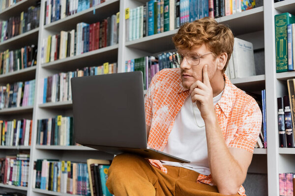 Young man engrossed in laptop studies.