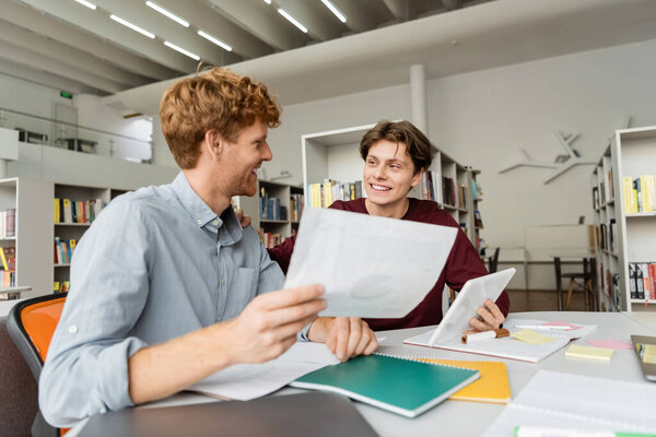 Два студента-мужчины, занятые учебой за библиотечным столом.