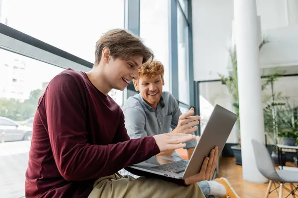 stock image Two male students engrossed in laptop screen, studying together.