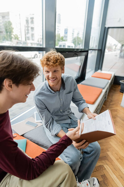 Two male students sit, absorbed in a book.