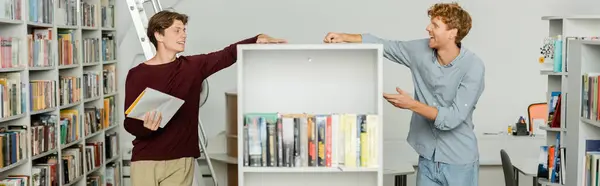 stock image Two young students exploring books in library.