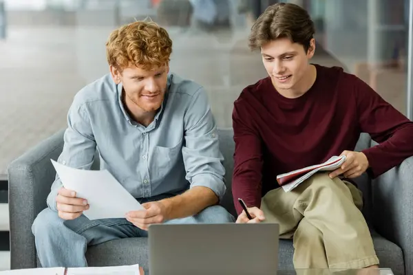 stock image Two men engrossed in laptop work on couch.