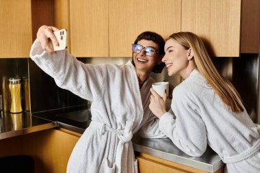 A young lesbian couple in bath robes taking a selfie in a luxurious hotel bathroom. clipart