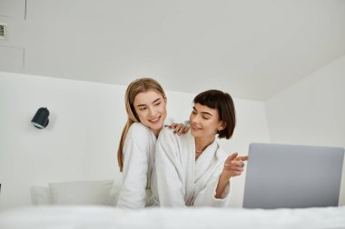 Banyolu lezbiyen bir çift rahat bir yatakta rahatlar, yakınlık ve yakınlık anlarını paylaşırlar..