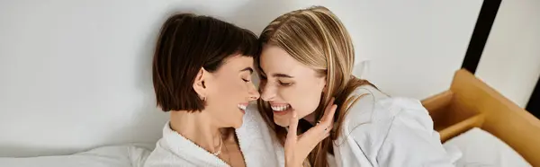 stock image Two women, a beautiful lesbian couple, lay peacefully on a bed in elegant white robes.