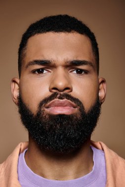 Sakallı şık bir Afro-Amerikan adam canlı bir arkaplana karşı güvenle poz veriyor..