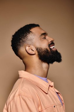 Handsome African American man with beard in stylish pink shirt posing against vibrant backdrop. clipart