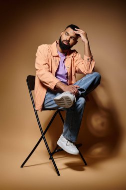 Yakışıklı Afro-Amerikan adam koltukta oturuyor, el üstünde, canlı arka planda..