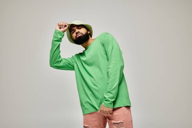 Yeşil tişörtlü ve pembe şortlu yakışıklı Afro-Amerikan adam rahat poz veriyor..