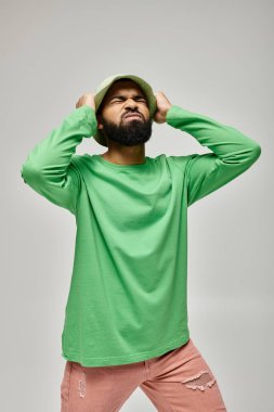 Yakışıklı Afrikalı Amerikalı erkek, canlı arka plana karşı şık pozlar veriyor..