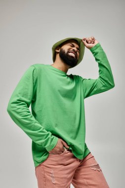 Yeşil şapkalı, şık Afro-Amerikan bir adam canlı arka planda poz veriyor..