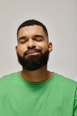 Sakallı yakışıklı Afro-Amerikan adam canlı arka plana karşı şık yeşil elbiseler giymiş..