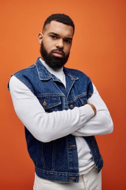 Yakışıklı Afrikalı Amerikalı erkek, canlı arka planda şık bir kot yelek giyiyor..