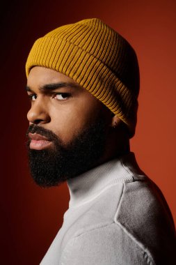 Moda kıyafetli, sarı şapkalı, sakallı yakışıklı adam, renkli arka plana karşı..