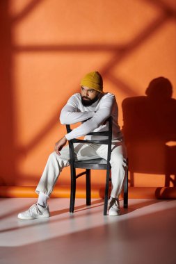 Yakışıklı Afrikalı Amerikalı adam moda kıyafetleriyle sandalyede oturuyor..