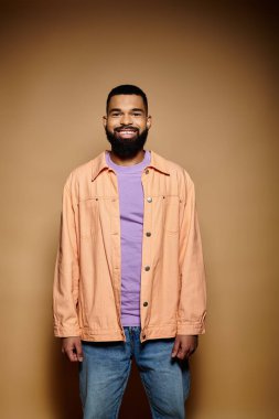 Sakallı adam canlı bir arkaplanda poz veriyor..