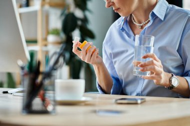 A middle aged businesswoman with short hair sits at a desk, taking a moment to hydrate with a glass of water during menopause. clipart