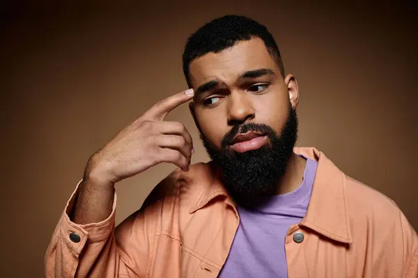 stock image Handsome African American man with beard wearing a purple shirt, striking a pose on a vibrant backdrop.