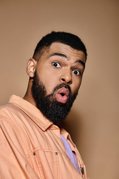 Handsome African American man looks surprised in trendy clothing against colorful background.