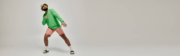 Яркий афроамериканец в стильной зеленой толстовке энергично танцует.