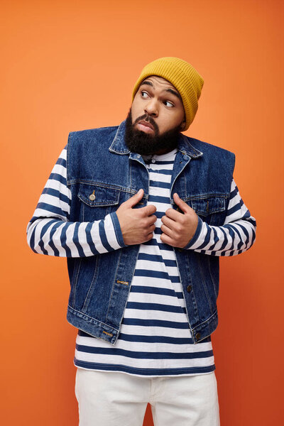 Handsome African American man in denim jacket and striped shirt in a vibrant setting.