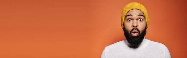 Handsome African American man in stylish outfit looking surprised.