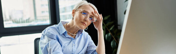 Middle-aged businesswoman with short hair intensely working on laptop during menopause in office.