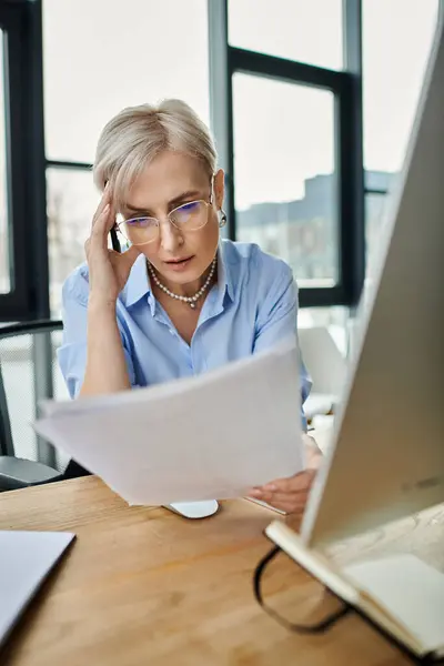 stock image A middle aged businesswoman with short hair sitting at a desk, feeling unwell during menopause